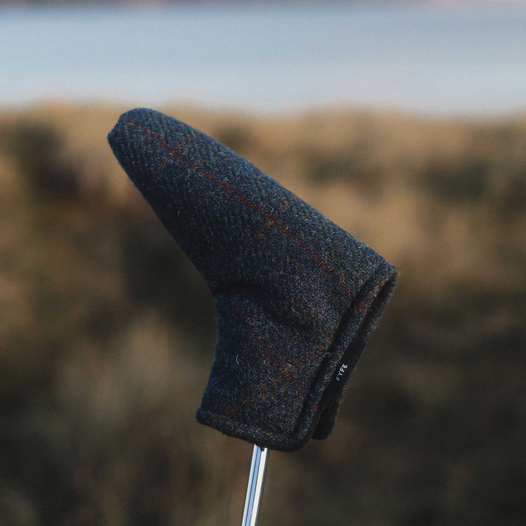 Golf club head cover on a golf club with a blurred natural background