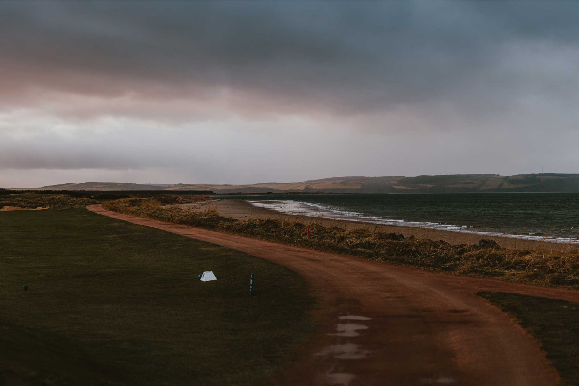 Nairn Golf Course with sea view  – A stunning view of Nairn Golf Course, showcasing the expansive green links stretching towards the coastline, with the calm sea and horizon in the background, highlighting the course’s coastal charm and breathtaking scenery.